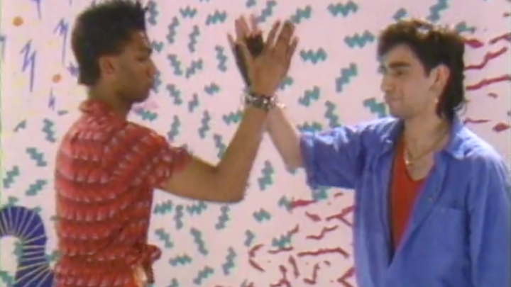 Two 80s breakdancers clap hands.