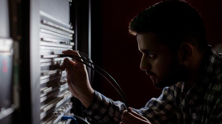 A man plugs an ethernet cable into a server.